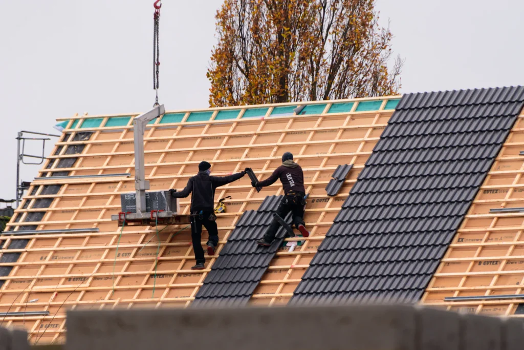 Dakdekkers leggen nieuwe dakpannen op een hellend dak